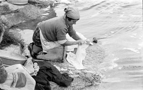 Muller  axeonllada lavando roupa ao carón dun rio.