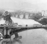 Fotomontaxe no que aparece un dinosauro atacando aos vehículos que circulan pola Ponte Nova.