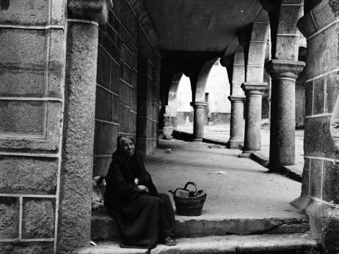 Mujer sentada en uno de los soportales de la Plaza García Boente de Ribadavia 